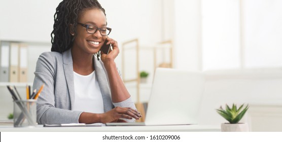 Lady Boss. Afro Businesswoman Talking On Cellphone While Working On Laptop In Modern Office, Wide Horizontal Banner, Panorama With Free Space