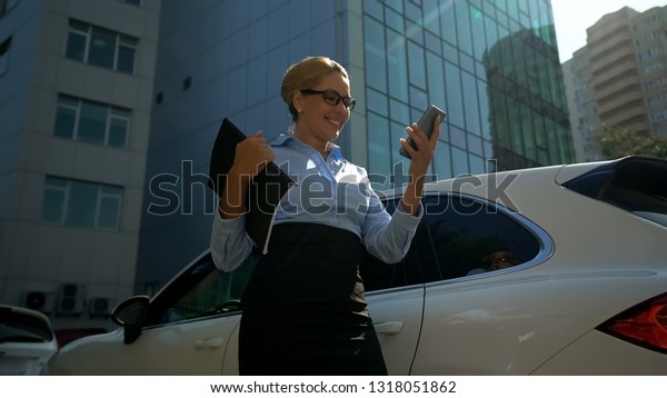 Lady boss smiling reading good news on her\
smartphone, successful\
meeting