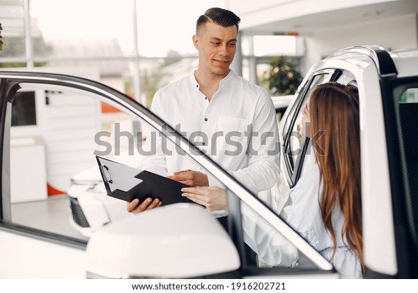 Lady in a car salon. Woman\
buying the car. Elegant woman in a white blouse. Manager with a\
client