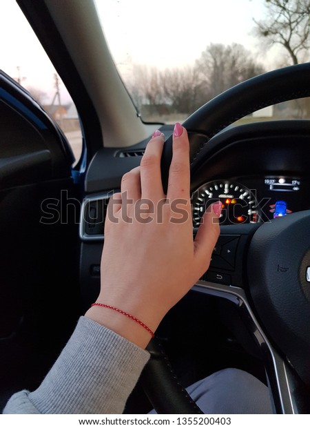 Lady in car.\
Women hand on the steering\
wheel