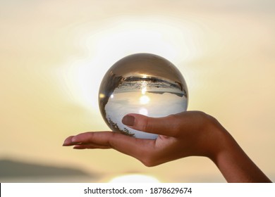 lady catch the crystal ball on her hand beside Patong beach during sunset
