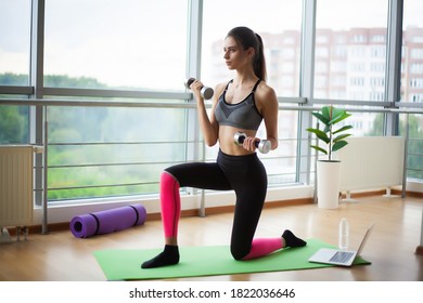Lady does exercises at home in front of a laptop to maintain optimal weight and good physical shape