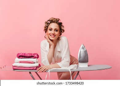 Lady In Elegant Outfit With Smile Looks Into Camera And Leans On Ironing Board