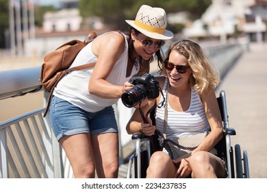 lady with friend in wheelchair reviewing photos on camera - Powered by Shutterstock
