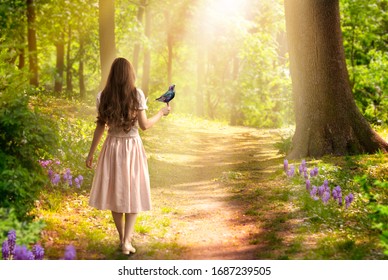 Lady girl with long hair in dress with bird in hand walking in fantasy enchanted fairy tale spring forest with blooming flowers and sun rays, mysterious road goes through trees in magical elvish wood