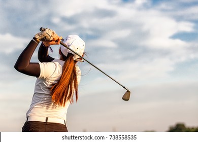 lady golfer swing  with a blue sky.