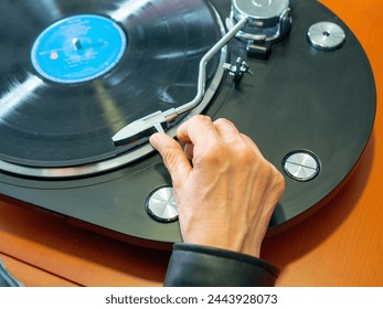 Lady hand holding the tonearm of her turntable ready to play a vinyl record