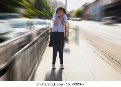 Lady having a panic attack outside in public space holding her hands on her face. Scared person feeling despair on a sidewalk. Anxiety issues or mental problems concept