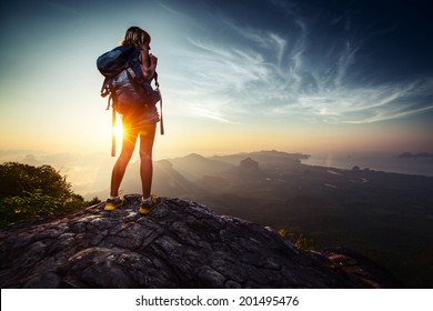 Lady hiker relaxing on top of hill and enjoying sunrise over the valley