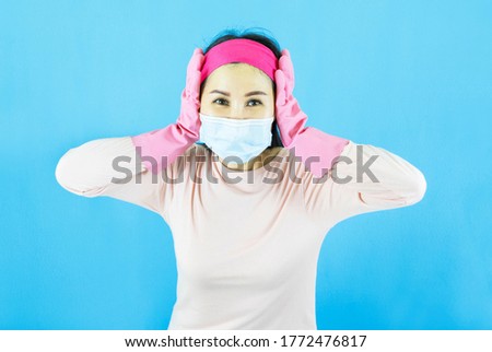  lady house wife maid in face mask,latex gloves on hands, crazy bad mood dirty messy flat wear headband pink shirt isolated blue color background