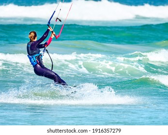 Lady kiteboarder captured kitesurfing in high wind off Kitebeach, Bloubergstrand, Table Bay, Cape Town, South Africa.