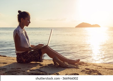 Lady With A Laptop On The Beach On The Sunset