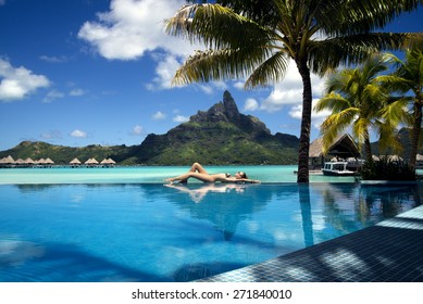 Lady Laying On The Edge Of Infinity Pool  On The Beach Of A Luxury Vacation Resort With View On The Otemanu Mountain On The Tropical Island Of Bora Bora, Near Tahiti, French Polynesia, Pacific Ocean