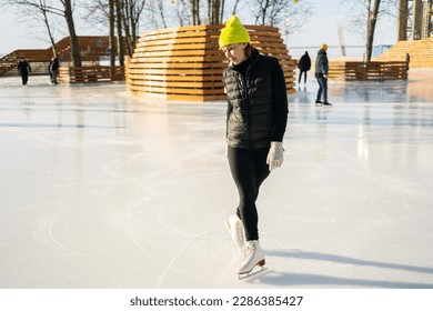 Lady learn to skate on ice. A man in a sports black uniform and a yellow hat. - Powered by Shutterstock