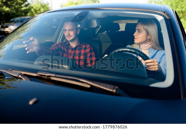 Lady and male\
instructor in car, driving\
school