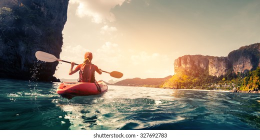 Lady paddling the kayak in the calm tropical bay at sunset
