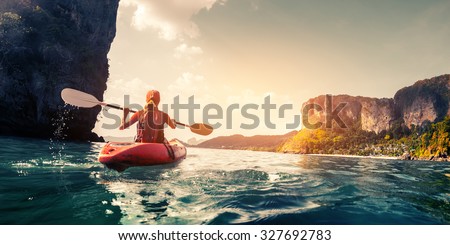 Lady paddling the kayak in the calm tropical bay at sunset