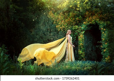 Lady princess stands in fantasy summer forest. arch from natural green leaves tree. Long blond hair.  magic goddess