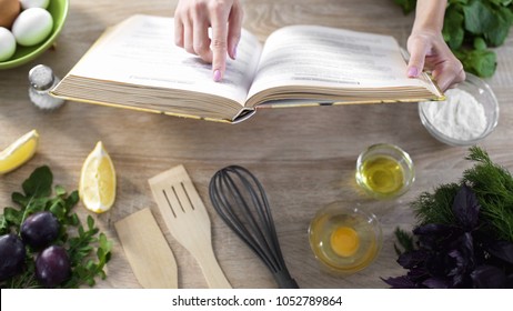 Lady reading pizza recipe in culinary book at home with kitchenware on table - Shutterstock ID 1052789864