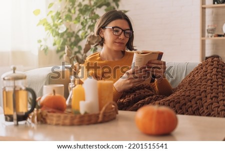 Lady reads a book in blanket on the sofa in front of teapot and candles. Photo stock © 