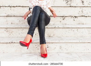 Lady with red high heel shoes sitting on stairs