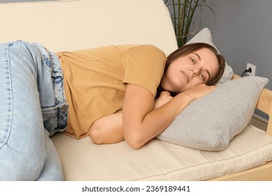 Lady resting. Boredom relief. Sleepy girl. Health break. Comfy sofa rest. Daytime calm. Caucasian woman lying on sofa in living room sleeping in home interior.