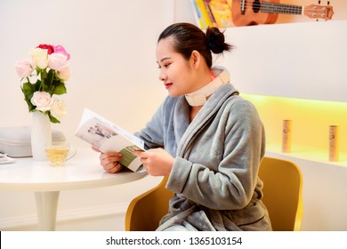 Lady Sitting On The Chair Reading A Book With Electric Neck And Shoulder Massage Machine 