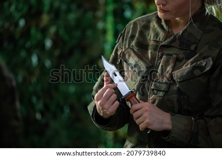 A lady soldier checks how sharp her bayonet is, which will be mounted on a rifle.