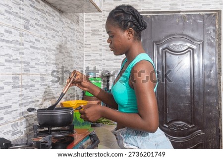 Lady standing by the stove, checking a pot while preparing breakfast