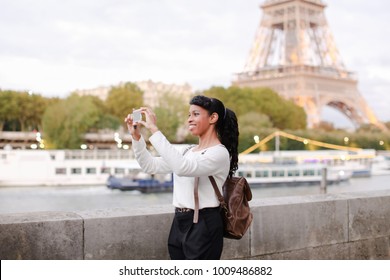 Lady Standing On Embankment Not Far From Eiffel Tower In Paris And Watching Pictures Of Landmarks Made During Day On Mobile. Girl Came To France To Visit Pen Pal And Decided To Go On City Tour. Pretty