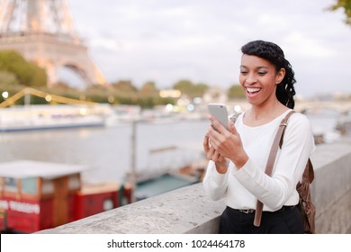 Lady Standing On Embankment Not Far From Eiffel Tower In Paris And Watching Pictures Of Landmarks Made During Day On Mobile. Girl Came To France To Visit Pen Pal And Decided To Go On City Tour. Pretty