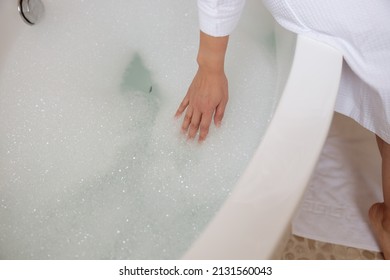 Lady is testing temperature of water in bathroom - Powered by Shutterstock