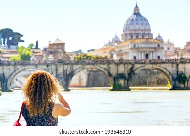 Lady tourist photographs St Peter's basilica in Vatican City, Rome, Italy.  Adult girl traveler takes picture of Rome in summer. People walk in sunny Rome, Europe. Theme of tourism, travel, photo. - Powered by Shutterstock