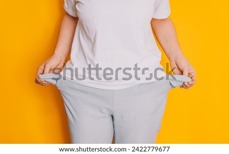 Lady turned out her empty pockets against a yellow background.