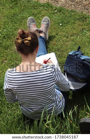 lady using a scetch pad and pencil drawing a outdoor scene image taken from above