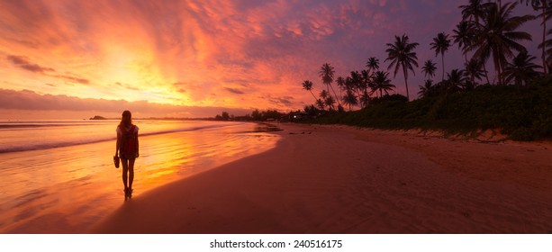 Lady Walking On The Wet Sandy Beach During Sunset