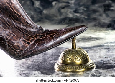 Lady Wearing Snake Skin Boots Ringing Brass Service Bell.