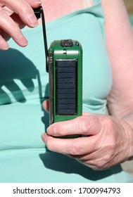 A Lady Winding Up The Solar Powered Radio