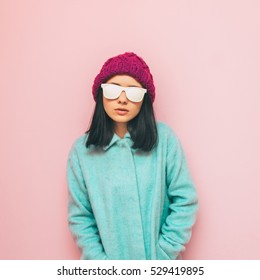 Lady In Winter Clothing: Oversize Mint Coat And Purple Hat On Pink Wall. Fashion Of 90's. Pastel And Minimalism.