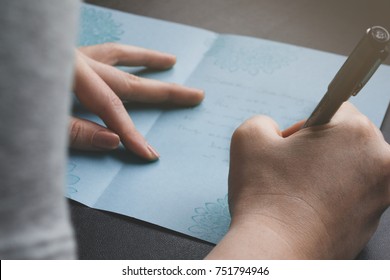 Lady Writing A Hand Crafted Card To Family Or Friend. View Over Her Shoulder. Close Up Of Card And Hands. Concept.