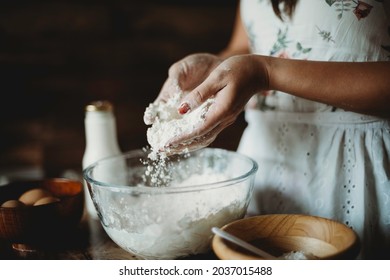 Lady's hands sprinkling and pouring flour into mixing glass bowl.Worker preparing dough.Professional baker in bakehouse.Kneading process.Woman preparing cake baking ingredients. - Powered by Shutterstock