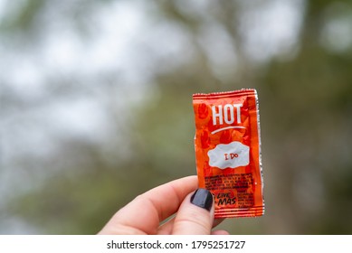 LAFAYETTE, L.A. / USA -  MARCH 3, 2020: A Closeup View Of A Caucasian Lady's Hand, Holding A Small, Orange Packet Of Taco Bell Hot Sauce, Outdoors, During The Spring, In South Louisiana.