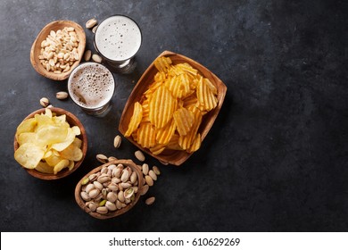 Lager beer glasses and snacks on stone table. Nuts, chips. Top view with copyspace - Powered by Shutterstock
