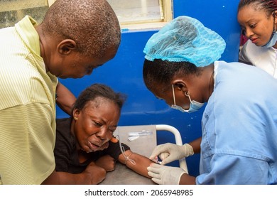 Lagos, Nigeria - September 6, 2021: African Lady Wearing Black in Severe Pains being Wheeled in for an Emergency Operation. Tears due to Abdominal Pains. Ruptured Appendicitis
