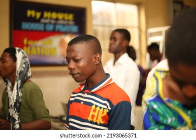 Lagos, Nigeria-August 21, 2022: A Teenager In An African Church With Eyes Closed Praying With All His Heart