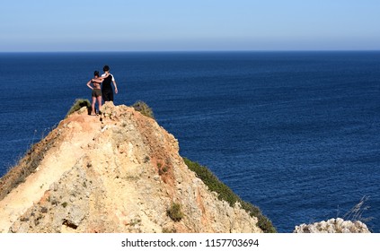 Lagos, Portugal - July 8 2018: Teenage Boy And Girl Standing On Rock Over The Ocean 
