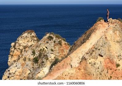 Lagos, Portugal - July 8 2018: Teenage Girl With Sun Glasses Standing On Rock Over The Ocean 
