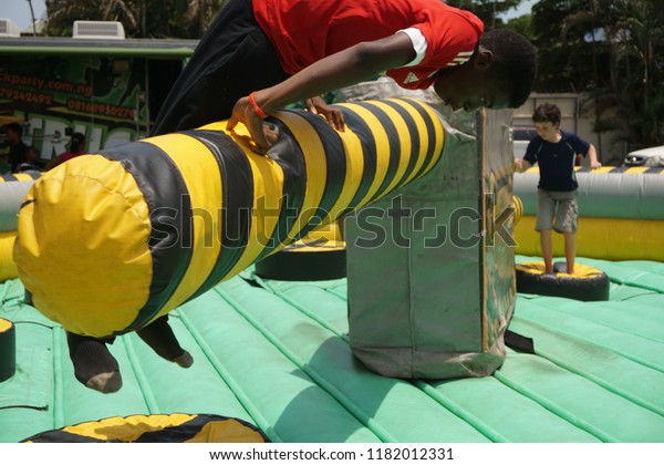 Lagos/Nigeria-April 16th, 2016: A group of\
children playing on the inflatable sweeper twister game at a\
carnival. Player hit by the rotating pole will be eliminated. Made\
famous by Wipeout\
franchise.