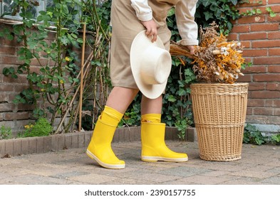 Lags in yellow boots stand near wicker basket in the autumn garden - Powered by Shutterstock