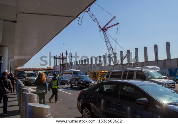 Laguardia Airport, New York, USA-\
October 14, 2019 - construction cranes working as passengers get\
into vehicles and cabs at Laguardia airport in New York\
